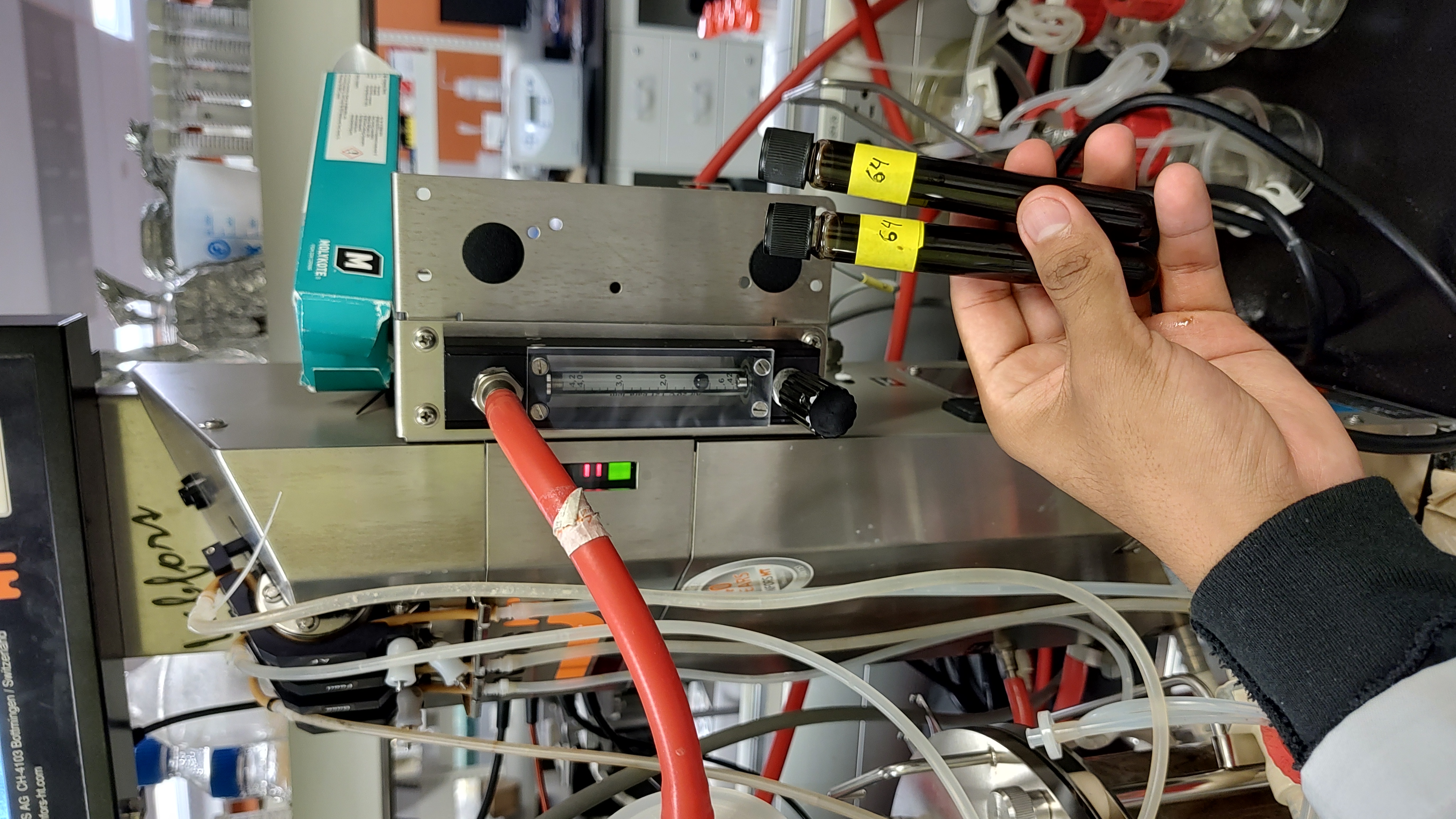 An analyst in a laboratory drawing a liquid sample from a fed-batch bioreactor culture