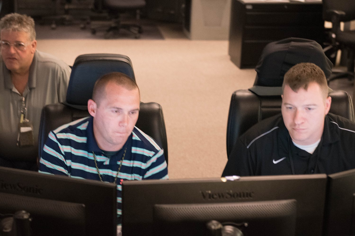 Operators seated at a bank of computer monitors in a plant control room, watching live process data.