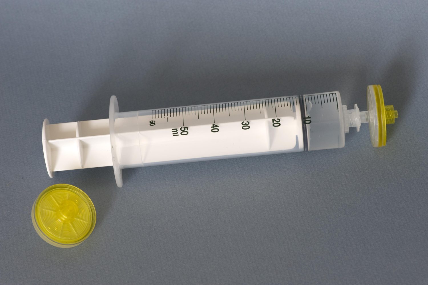 A disposable membrane filter capsule attached to the tip of a plastic syringe, with a second filter capsule beside it.